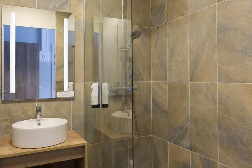 a bathroom with a sink and a glass shower at SOWELL HÔTEL L'Alpe Blanche in Vars