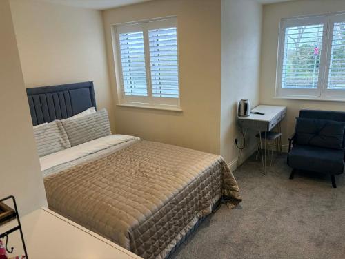 a bedroom with a bed and a desk and a chair at ROSE-WOOD Gatwick in Horley