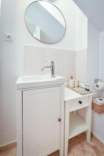 a white bathroom with a sink and a mirror at Casa Baritiu Rooms in Braşov