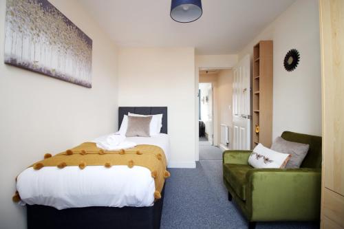 a bedroom with two beds and a green couch at Alicia's Way by Tŷ SA in Newport