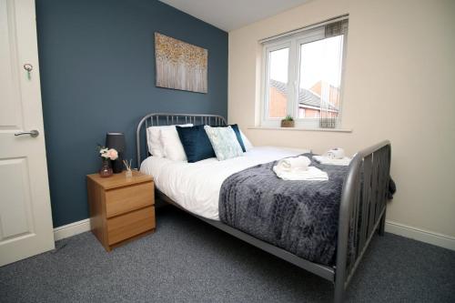 a bedroom with a bed with blue walls and a window at Alicia's Way by Tŷ SA in Newport