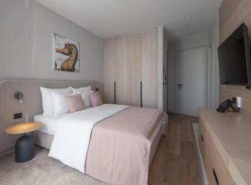 a bedroom with a large white bed and a television at Sea Star Budva in Budva