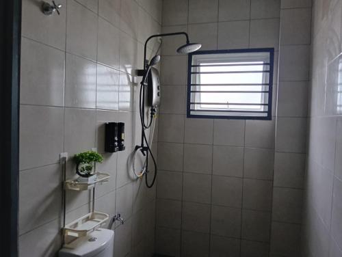 a bathroom with a shower and a toilet and a window at Seri Cempaka Homestay in Kluang