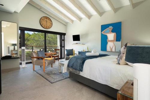 a bedroom with a bed and a clock on the wall at Topiary Lux Studio 16! in Herolds Bay