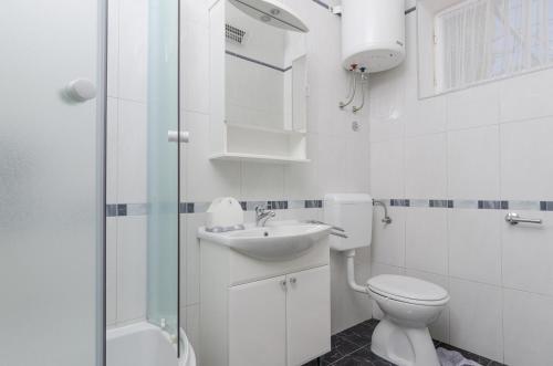 a white bathroom with a toilet and a sink at Holiday Apartment Maria in Orebić