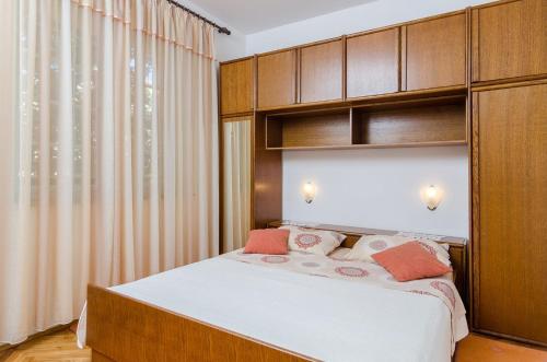 a bedroom with a bed and wooden cabinets at Holiday Apartment Maria in Orebić