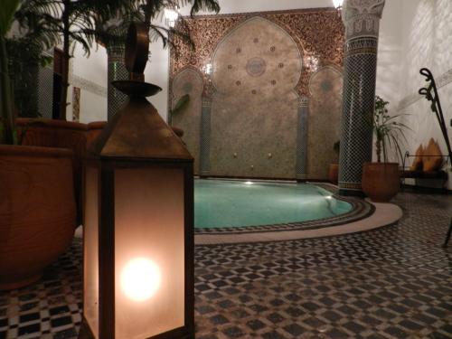 a swimming pool in a room with a light and a lantern at Riad Jamaï in Fès