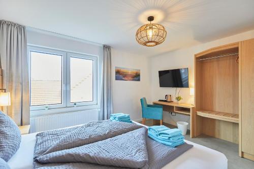 a bedroom with a bed and a desk and a television at Haus Antina - App 2 in Borkum