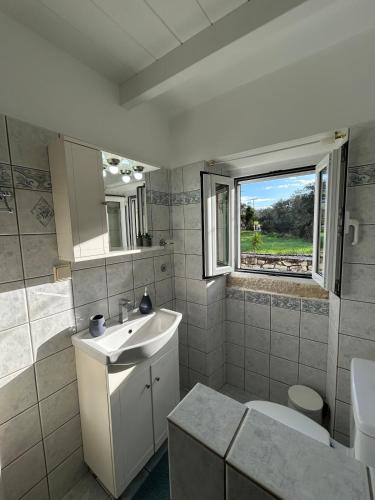 a bathroom with a sink and a toilet and a window at Loukas house Paxos in Boïkátika