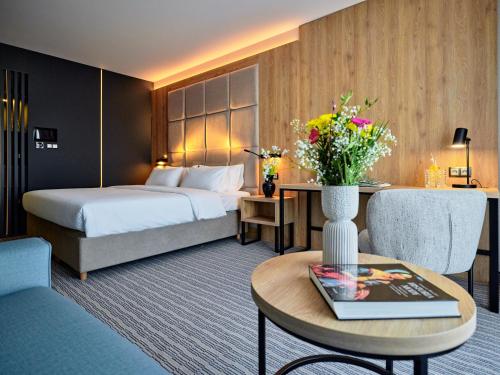 a hotel room with a bed and a table with a vase of flowers at Hotel Verde City in Koszalin