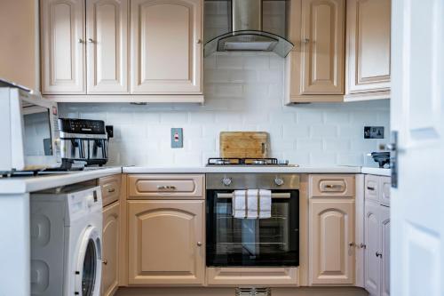 a kitchen with white cabinets and a stove top oven at Comfy 3 Bed House in Northampton