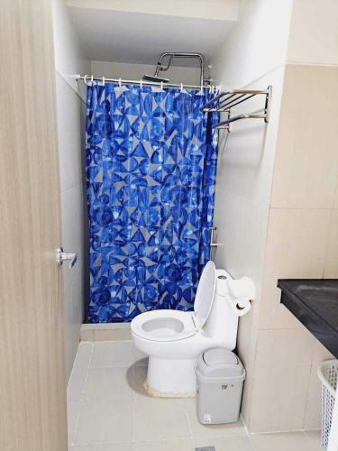 a bathroom with a toilet and a blue shower curtain at Coast Residences Roxas Boulevard Manila in Manila