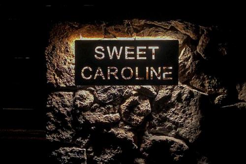 a sign that reads sweet carolina on a stone wall at Sweet Caroline in Villaverde