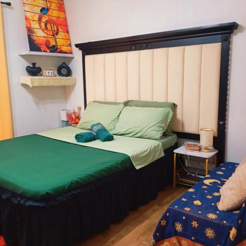 a bedroom with a bed with a green comforter at Amani Airport Haven - 726 in Pusok