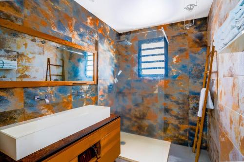 a bathroom with a sink and a mirror at LA MAISON DES JADES in La Saline les Bains