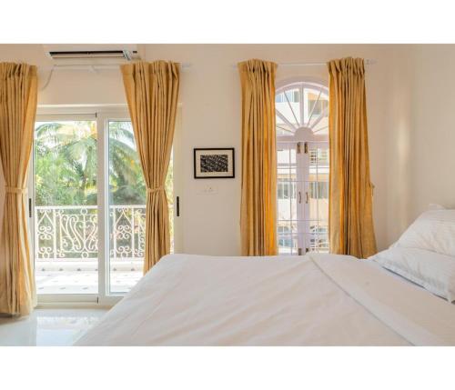 a bedroom with a bed and a balcony at Casa De Alegria Goa in Canacona