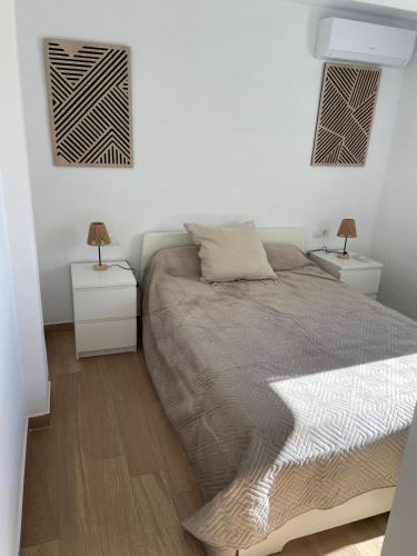 a white bedroom with a bed and two night stands at Europa A- 12º-23 in Cullera