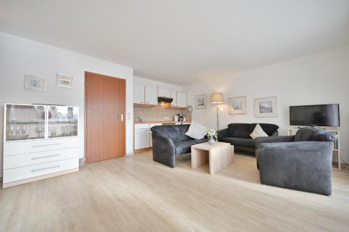 a living room with two black couches and a kitchen at FeWo Grytz in Dahme