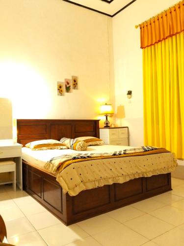 a large bed in a room with a yellow curtain at Wambuliga Homestay in Waha