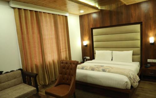 a hotel room with a bed and a chair at VijayLord's palace Badrinath in Badrinath
