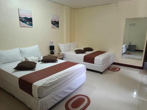 a bedroom with two beds and a mirror at D' TRAVELLERS Inn PUERTO in Puerto Princesa City