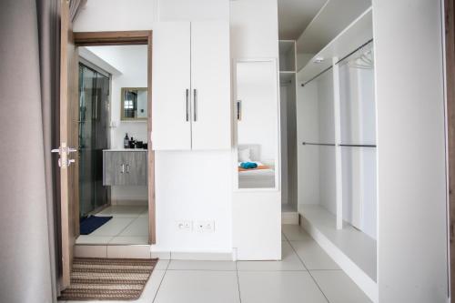 a kitchen with white cabinets and a refrigerator at Stylish Central Three Bed Duplex with Private Pool in Flic-en-Flac