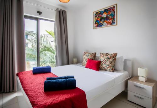 a bedroom with a white bed and a window at Stylish Central Three Bed Duplex with Private Pool in Flic-en-Flac