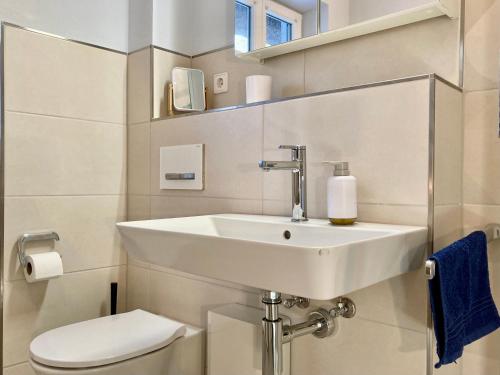 a white bathroom with a sink and a toilet at Achtern Diek 12b - Wohnung 5 in Müggenburg