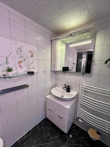 a white bathroom with a sink and a mirror at Ferienwohnung Heyne in Weinböhla
