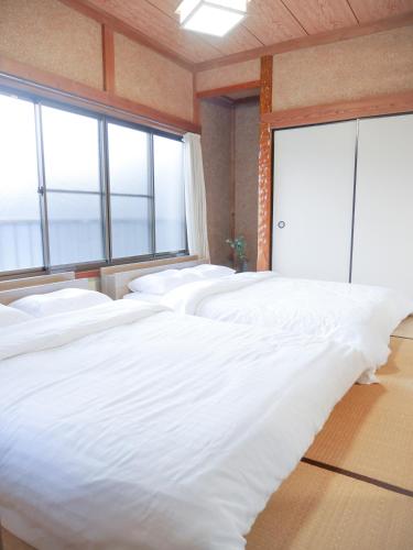 a row of white beds in a room with windows at FUNAKATA MINA House in Tateyama