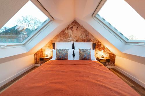 a attic bedroom with a bed with two windows at Design Loft mit Whirlpool - Einzigartig & Citynah in Krefeld