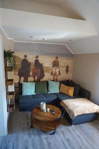 a living room with a blue couch and a painting at Wohnung Burghaus 5 OG in Krummhörn