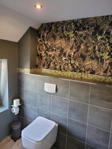 a bathroom with a toilet and a mural on the wall at Wohnung Burghaus 5 OG in Krummhörn