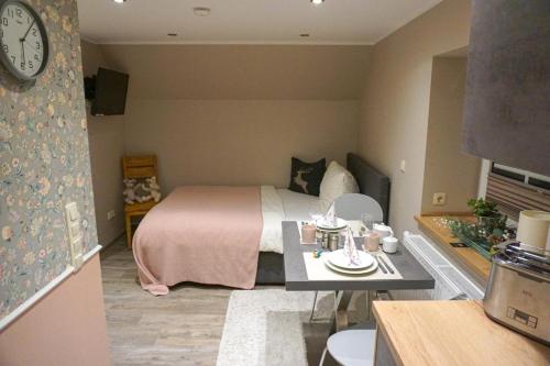 a small bedroom with a bed and a table with a clock at Wohnung Burghaus 3 OG in Krummhörn