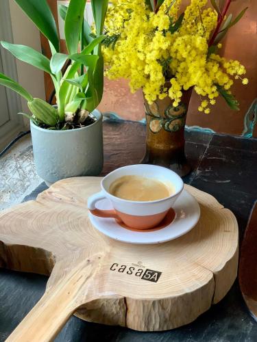Eine Tasse Kaffee auf einem Holztablett mit Blumen in der Unterkunft Casa 5A - Refúgio Intimo e privado com design e pátio acolhedor in Oliveira do Mondego