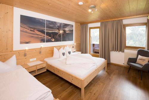 a hotel room with two beds and a chair at Appartement Moaeben - Panorama in Alpbach