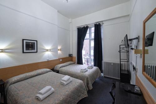a hotel room with two beds and a window at St George Hotel Paddington in London