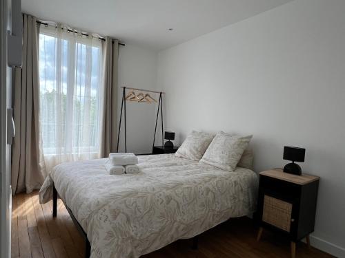 a bedroom with a large bed with white sheets and a window at Maison de ville à Etampes in Étampes