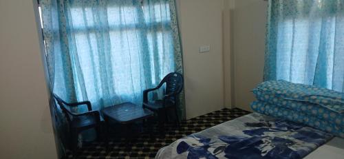 a bedroom with blue curtains and a bed and chairs at Snow Bound Home stay in Fagu