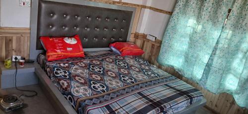 a bed with two red pillows on top of it at Snow Bound Home stay in Fagu