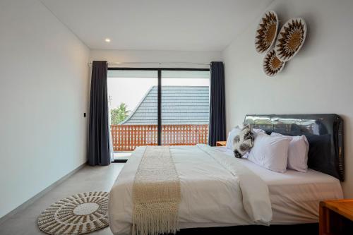 a bedroom with a large bed with a large window at Dkenyeri Villa by Aayan in Tanah Lot
