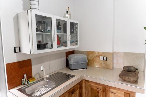 a kitchen with white cabinets and a sink at Villa Bee in Wennappuwa