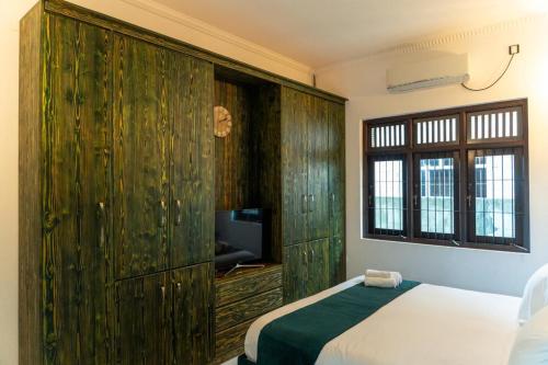 a bedroom with a bed and a large wooden cabinet at Villa Bee in Wennappuwa