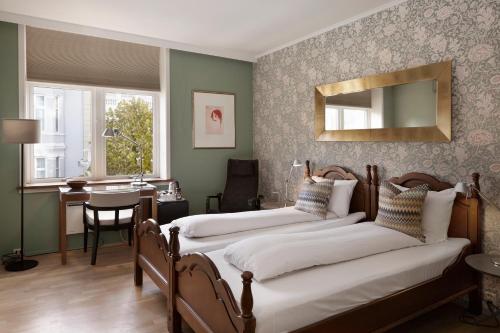 a bedroom with three beds and a table and a mirror at Hotel Park Bergen, Historic Hotels of Europe in Bergen