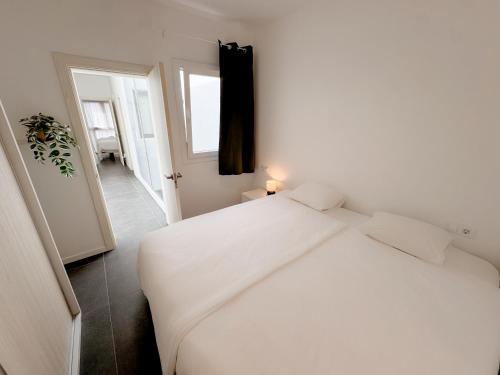 a white bedroom with a white bed and a window at apartment in La Santa, Lanzarote, village by the Sea in La Santa