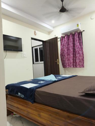 a bedroom with a large bed with a tv on the wall at Rr suites in Kākināda