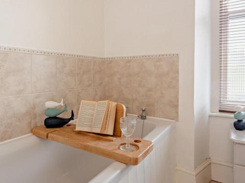 a bathroom with a bath tub with a book and a wine glass at Pembroke Lake House in Pembroke