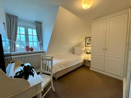 a small bedroom with a bed and a desk at Landhaus-Duenenhof in Rantum