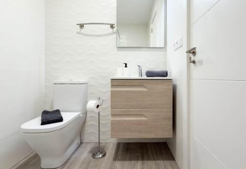 a white bathroom with a toilet and a sink at Guanarteme Vista Surf, Las Canteras in Las Palmas de Gran Canaria