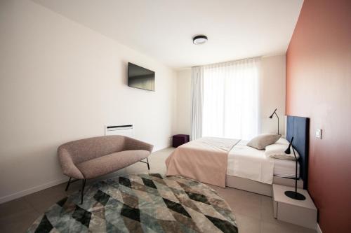 a bedroom with a bed and a chair and a window at Maison Selva - Corte Brunati Villetta Deluxe con piscina e garage in Salò